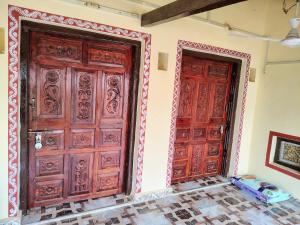 two wooden doors in a room with a tile floor at Kutchi Niwas homestay dholavira in Dholovira
