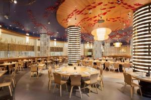 珠海市にあるChimelong Hengqin Bay Hotelのテーブルと椅子とシャンデリアのあるダイニングルーム