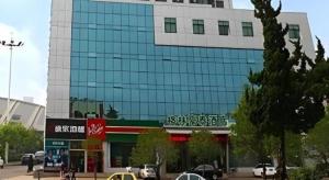 a large glass building with cars parked in front of it at GreenTree Inn Rizhao Train Station in Rizhao