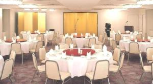 a room filled with tables and chairs with white table cloth at Marroad Inn Tokyo in Fuchu