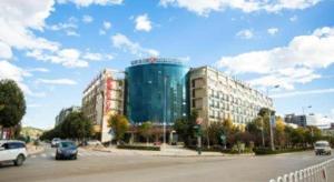 a large glass building on the side of a street at Jinjiang Inn select Hotel Kunming Economic Development Zone Kunming College in Kunming