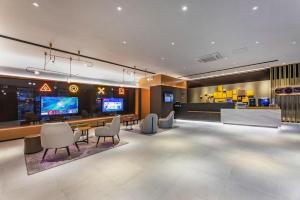 蘇州市にあるIU Hotel Wujiang Huadong Business City Tongliのテーブル、椅子、テレビが備わる広い客室です。