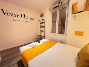a room with a bed with a yellow blanket at L'Ecrin de Clicquot, studio cosy au cœur d'Epernay in Épernay