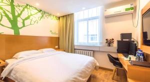 a bedroom with a bed and a desk and a window at Vatica TianJin NanKai Hardware Market West JieYuan Road Hotel in Tianjin