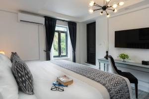 a bedroom with a bed with a television and a window at Luangprabang D'or Boutique Hotel in Luang Prabang