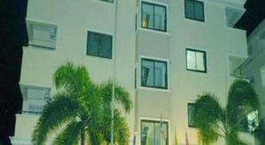 un grand bâtiment blanc avec des palmiers devant lui dans l'établissement Submukda Grand Hotel, à Mukdahan