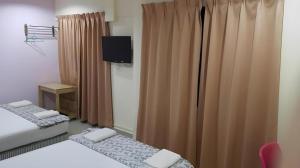 クアラルンプールにあるOYO 89717 Budget Star Hotelのベッド2台、テレビ、カーテンが備わる客室です。