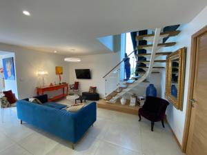 a living room with a blue couch and a staircase at L'Armande in Lédergues