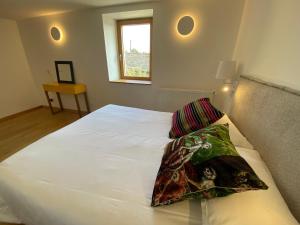 a bedroom with a white bed with two pillows on it at L'Armande in Lédergues +30 photos