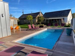 a swimming pool on a deck with chairs and a house at L'Armande in Meljac
