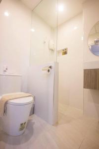a white bathroom with a toilet and a mirror at Baan Khun Nine in Ratchaburi