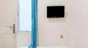 a flat screen tv on a wall next to a window at Super OYO 91074 Stariez Senen Syariah in Jakarta