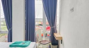 a room with a bed and a window with blue curtains at Hotel O Erbee Inn in Pamanjengang