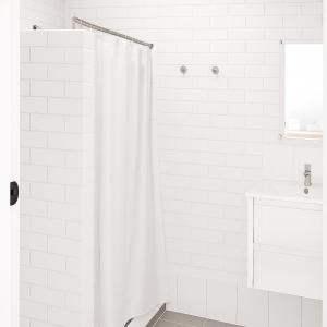 une salle de bain blanche avec un rideau de douche et un lavabo dans l'établissement Busselton Motel, à Busselton