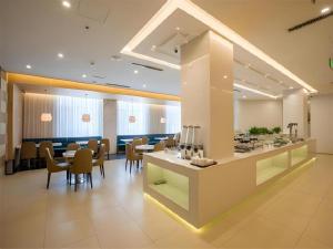 Jinjiang Metropolo Hotel Shenyang Country Garden Datong Lake Subway Station Branch في شنيانغ: مطعم يحتوي على طاولات وكراسي في الغرفة
