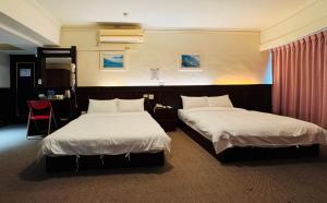 une chambre d'hôtel avec deux lits et une chaise rouge dans l'établissement 奇萊大飯店 Chuline Hotel, à Hualien