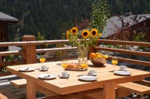a wooden table with a vase of sunflowers and a bowl of fruit at Adelaide A 03 in Grimentz