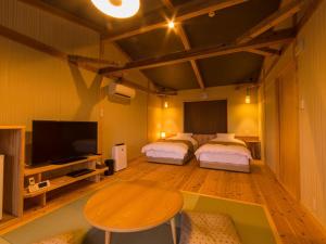 a room with two beds and a table and a tv at Isaribinoyado Seaside Kancho in Wakayama +55 photos