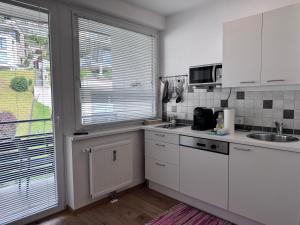 une cuisine avec des armoires blanches, un évier et une fenêtre dans l'établissement Apartment Nera - Zell am See, à Zell am See