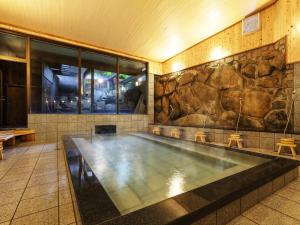 a large swimming pool with a stone wall at Yubaraonsen Yubaranoyado Komeya in Maniwa