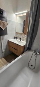 a bathroom with a bath tub and a sink at Un coin de paradis au pied des pistes avec balcon in Métabief