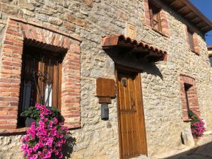 un bâtiment en briques avec une porte et des fleurs dans une fenêtre dans l'établissement Genciana, Casa Rural con encanto en La Montaña Leonesa, à Cuevas de Viñayo