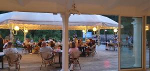 a group of people sitting at tables on a deck at Camping Le Gallo Romain in Barbières