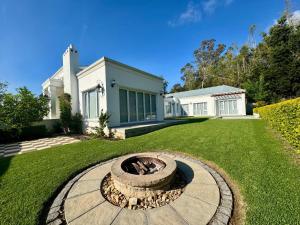 Un jardín con una fogata frente a una casa. en Bergzicht Villa, en Swellendam