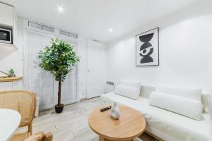 a white living room with a white couch and a table at Les Lilas Appartement 1 chambre wifi et confort in Les Lilas