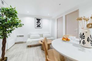 a white living room with a table and a couch at Les Lilas Appartement 1 chambre wifi et confort in Les Lilas