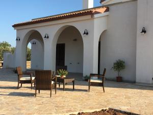 un patio con sillas y una mesa frente a un edificio en Villa Elia - Tenuta Le Scerze - Salento Homes en Borgagne