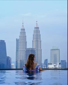 クアラルンプールにあるThe Luxe Infinitum By Elite Home KLCCの市街の景色を望むインフィニティプールの女性