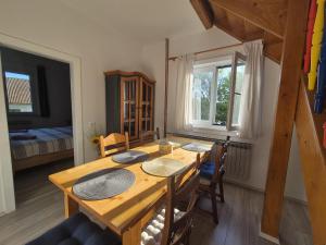 a dining room with a wooden table and a bedroom at Kuća Šarenka in Kupjak
