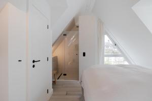 een witte slaapkamer met een bed en een raam bij Sylter Strandholz in Westerland