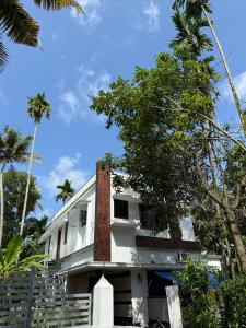una casa con palmeras delante en Varghese staycation, en Ernakulam
