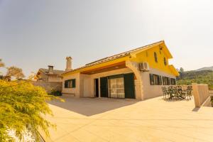 a yellow house with a patio with tables and chairs at A Casa dos Amigos - Termas São Vicente in Penafiel