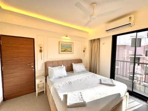 Un dormitorio con una cama y una ventana grande. en Beige 1BHK Family Retreat - Gym, Pool Access - Near Candolim Beach, en Candolim 34 fotos más