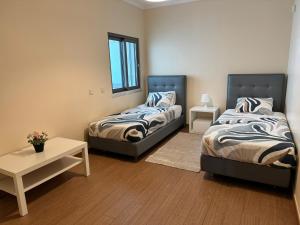 a bedroom with two beds and a table and a window at Brisa do Mar - 2BR Sea Front Luxury Apartment in Quarteira