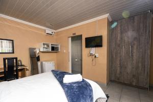 une chambre avec un lit et une télévision au mur dans l'établissement 166 Klipspringer Guest house, à Germiston