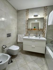 a bathroom with a sink and a toilet and a mirror at Brisa do Mar - 2BR Sea Front Luxury Apartment in Quarteira
