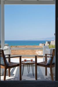 a patio with chairs and a table and a view of the beach at Selinofos in Naxos Chora