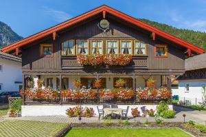 une maison avec beaucoup de fleurs devant dans l'établissement Ferienwohnungen Weiß, à Mittenwald