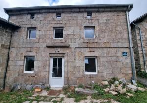 an old brick building with a white door at L'Ecole Buissonnière de Mazalibrand in Bronac