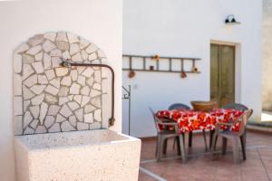 comedor con mesa, sillas y pared de piedra en Casa Vacanza Lu Mare e Lu Ientu, en Casamassella