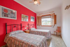 two beds in a room with red walls at Villa Padial in Torrox +17 photos