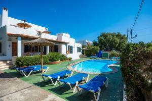 a swimming pool with chairs and a table and an umbrella at Apartamento Felipe 1-4 in Cala d´Or