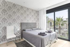Un dormitorio con una cama y una silla y una ventana. en Belle, en Playas de Orihuela