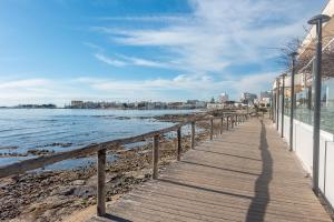 a boardwalk on the beach with a city in the background at Mare e Frescura Sea View in Porto Cesareo