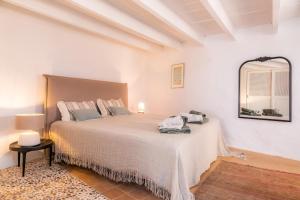 a white bedroom with a large bed with a mirror at Casa Max in Artá