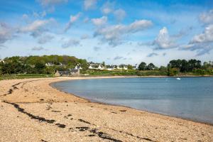 a beach with a rocky shore with houses in the background at Charmante maison de pecheur in Ploubazlanec